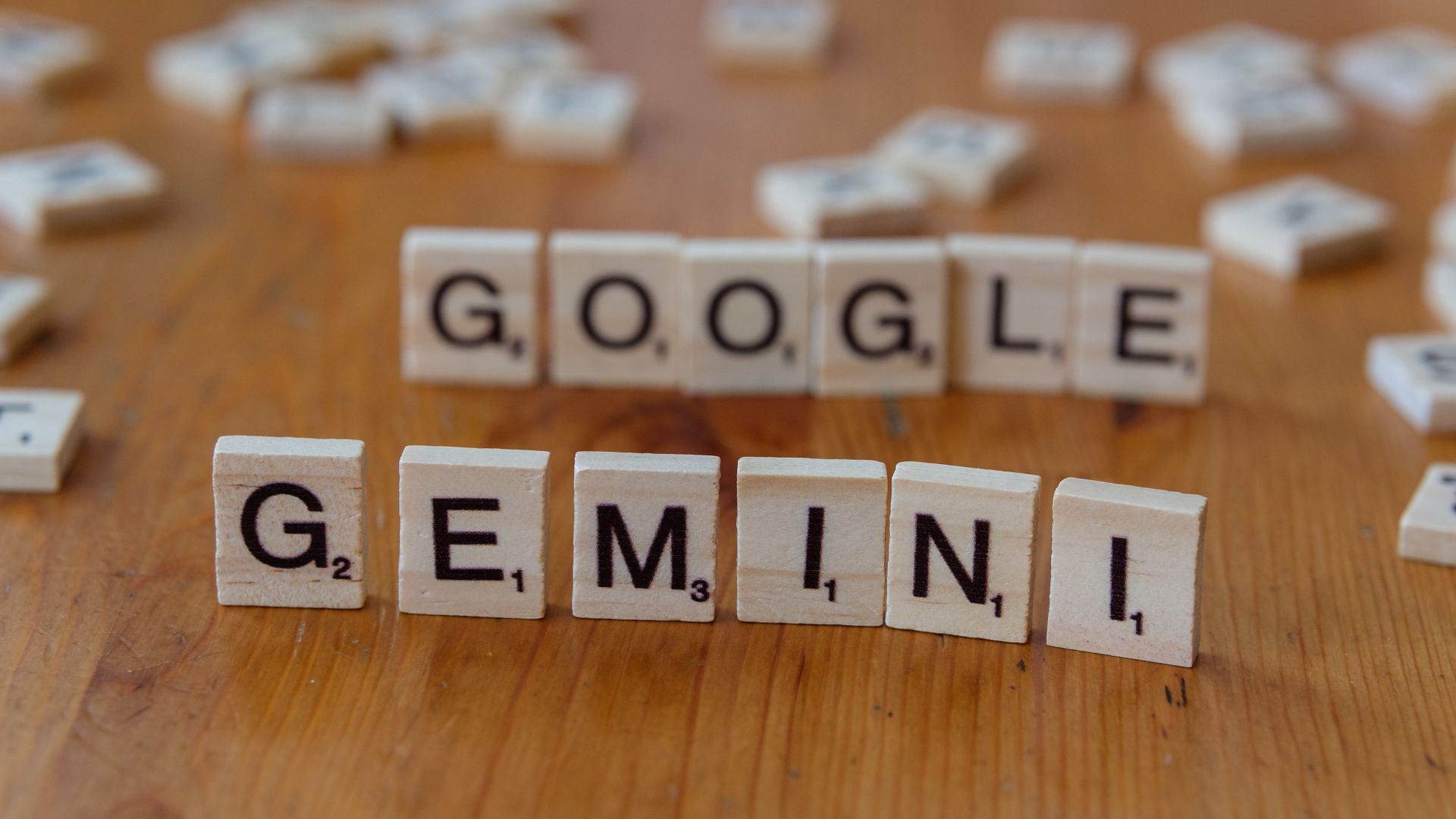 Scrabble tiles spelling the words Google and Gemini on a wooden table