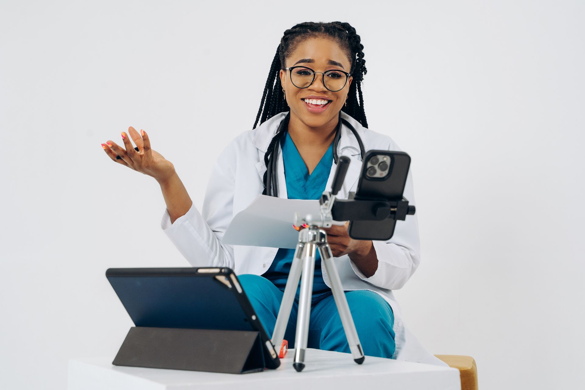 Doctor in scrubs recording content on a smartphone mounted on a tripod