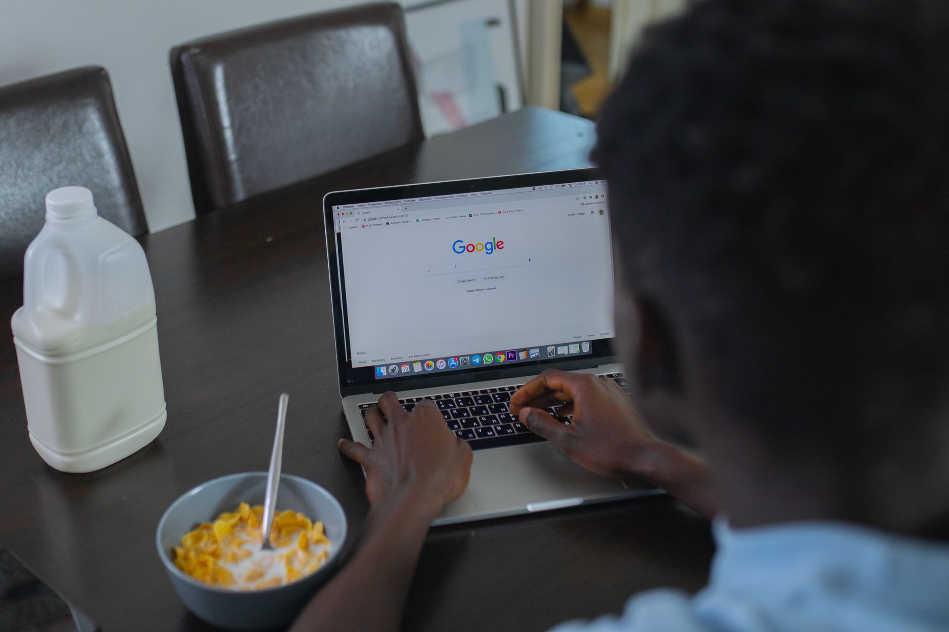 Person searching Google on a laptop at a kitchen table